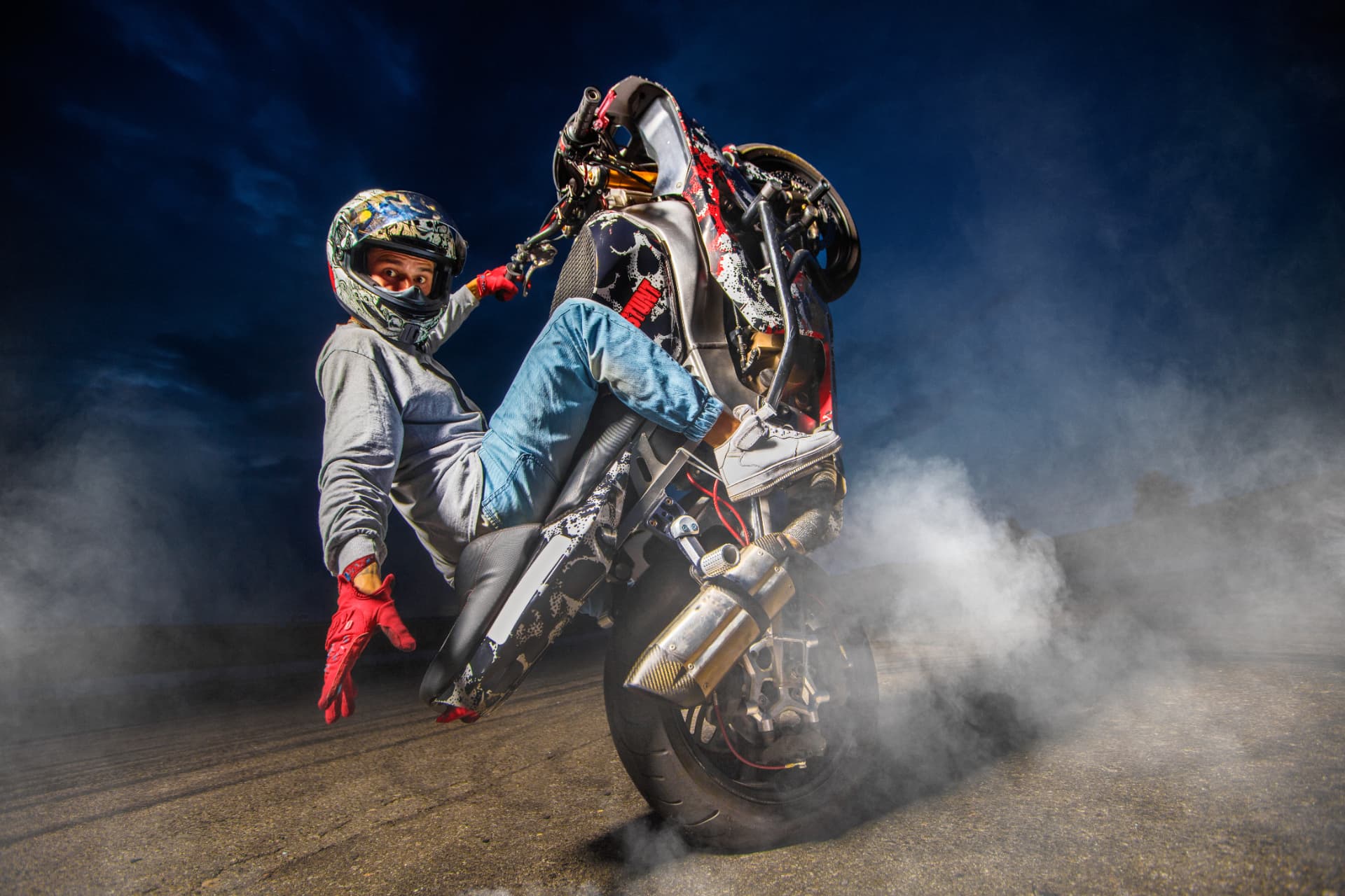 Stunt motard en wheelie dans la fumée, sous les projecteurs