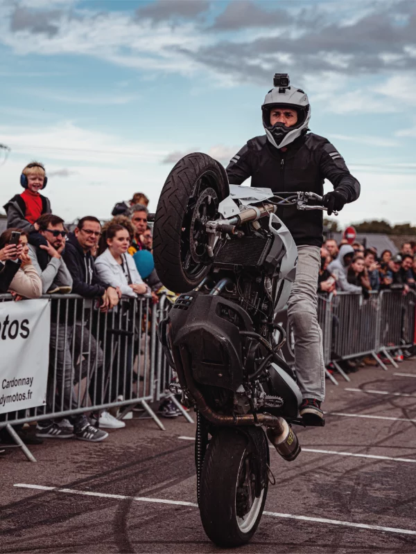 BigJim en figure de stunt moto, roue avant levée, au festival