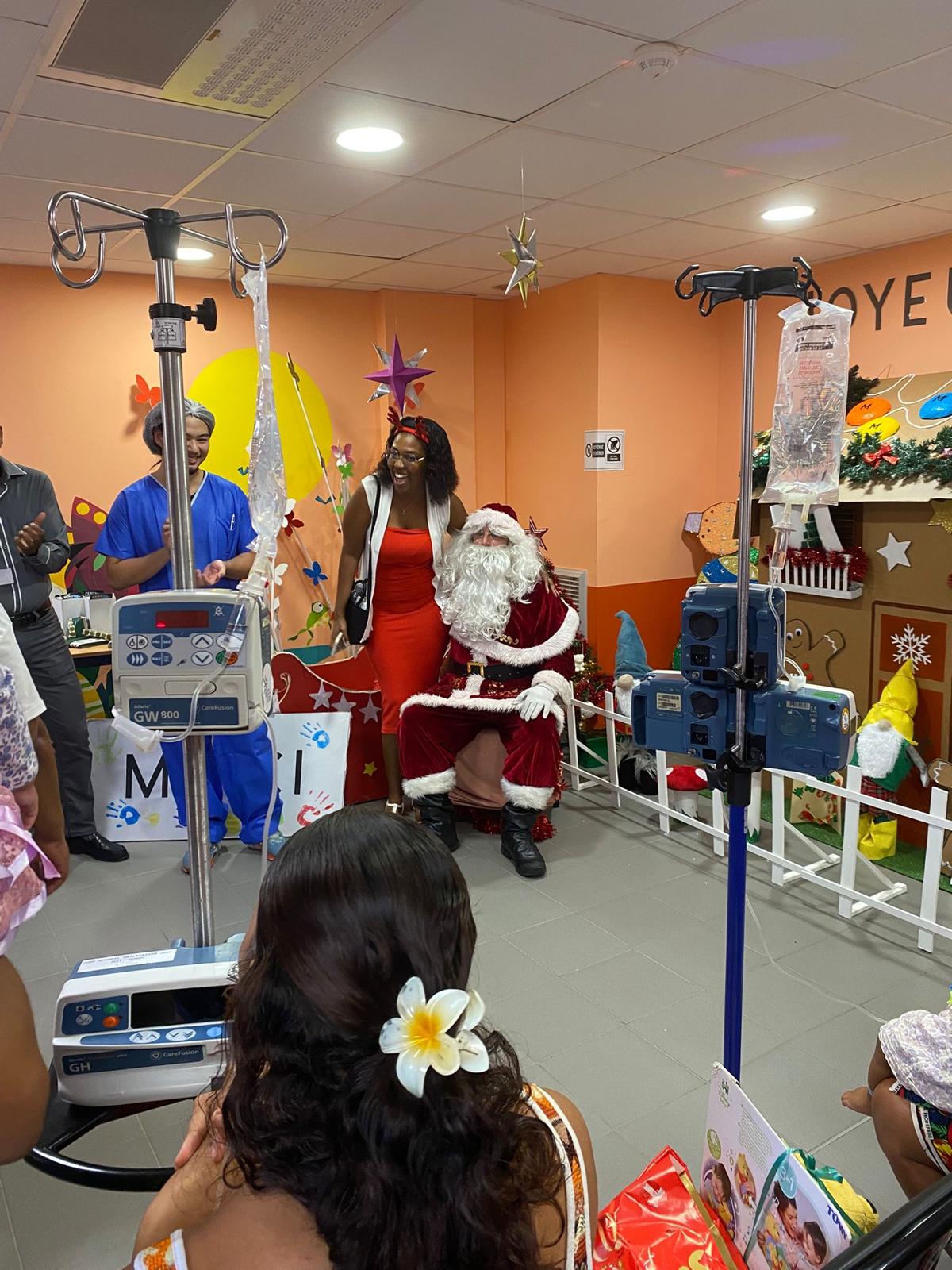 Père Noël assis dans le service pédiatrique entouré de l'équipe — KdoRide